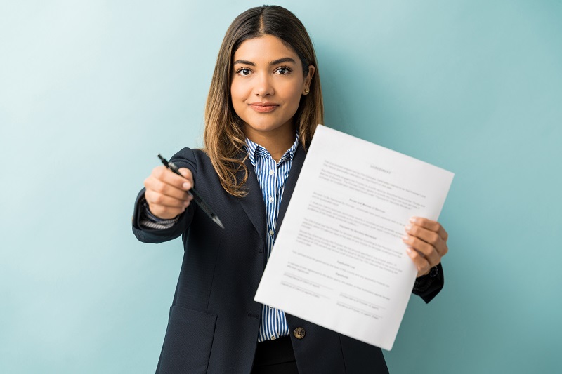 חתימת חוזה עבודה אישה מביאה עט לחתום על חוזה עבודה- חשוב לבדוק את חוזה עבודה מול עו"ד לעינייני עבודה